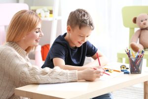 Female psychologist working with boy suffering from autistic disorder